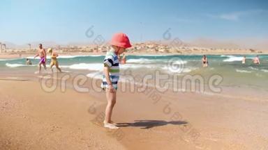 4k慢动作视频：欢快的幼儿男孩站在海边玩海浪